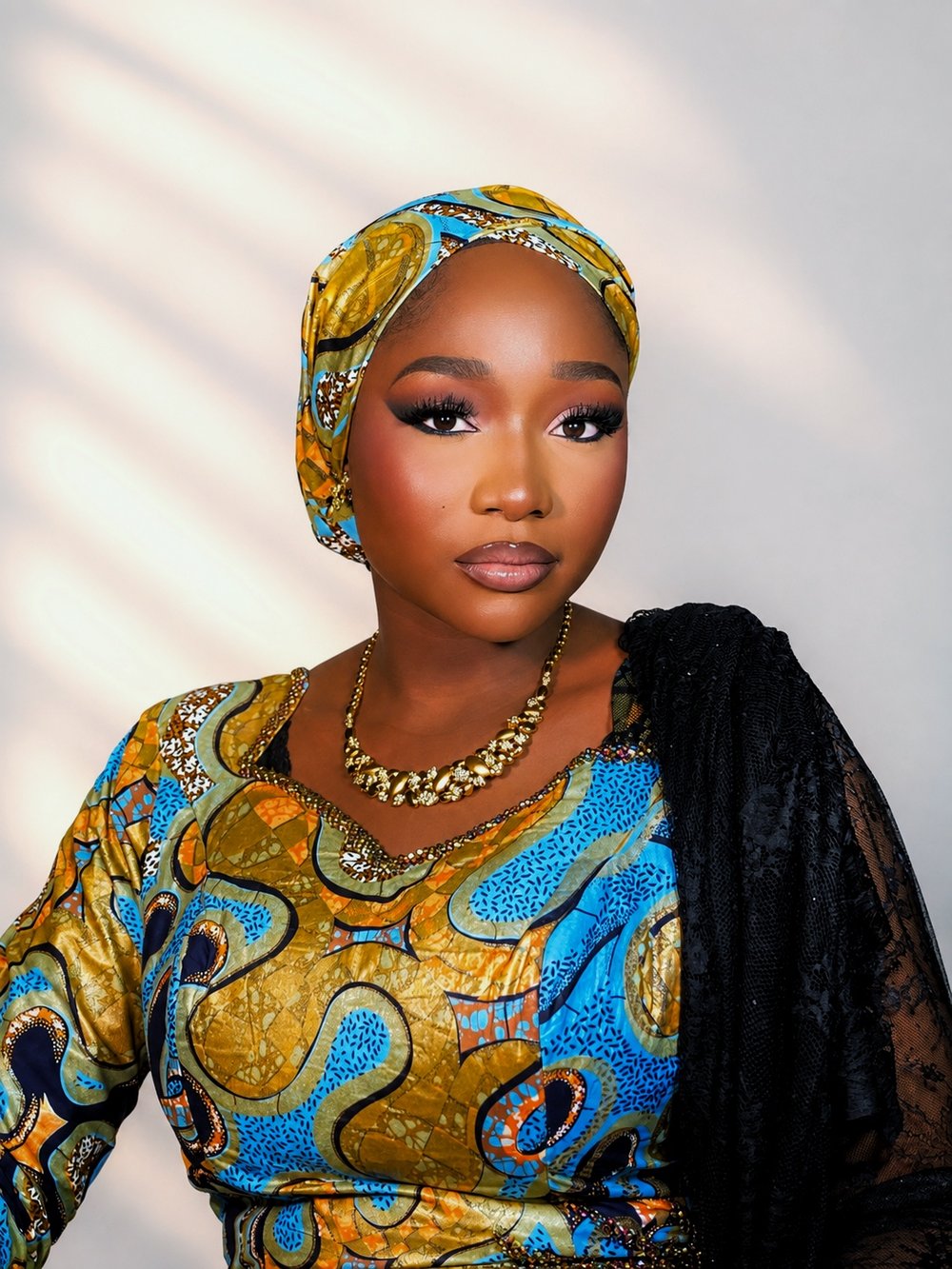 Glam makeup by glamby_meemah, model in a gold and blue ankara headwrap with a soft smoky eye