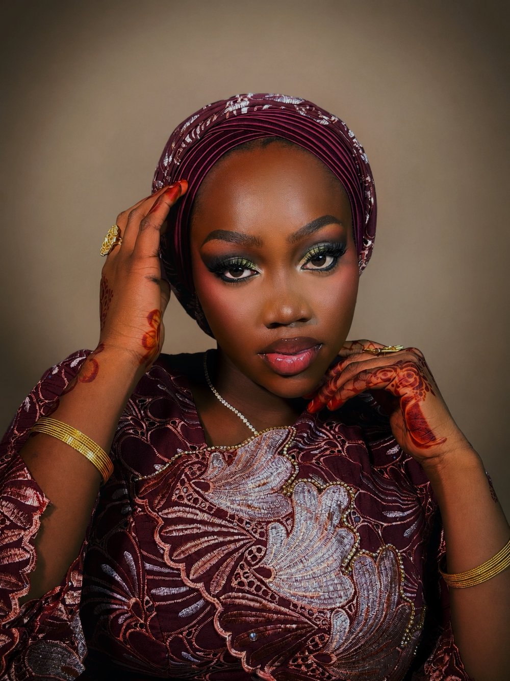 Glam makeup by glamby_meemah, model in a wine velvet headwrap with green-gold smoky eye and henna-adorned hands