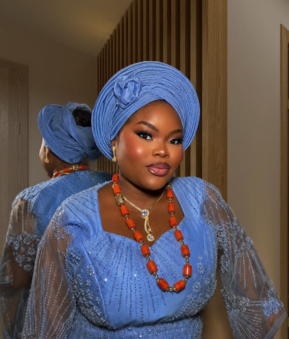 Glam makeup by glamby_meemah, bride in a blue aso-oke gele and beaded coral necklaces