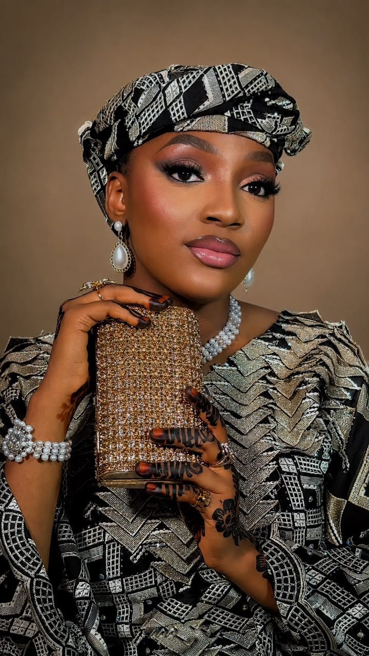 Glam makeup by glamby_meemah, model in a black and gold geometric headwrap with pearl jewelry and henna-adorned hands